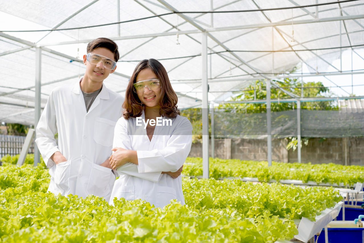 Smiling young woman standing in greenhouse