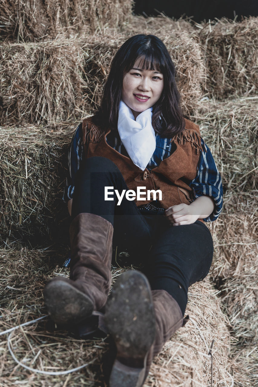 FULL LENGTH OF WOMAN SITTING ON FIELD IN WINTER