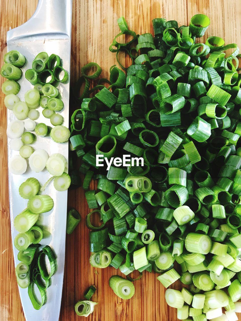 Directly above shot of chopped spring onions by knife on table