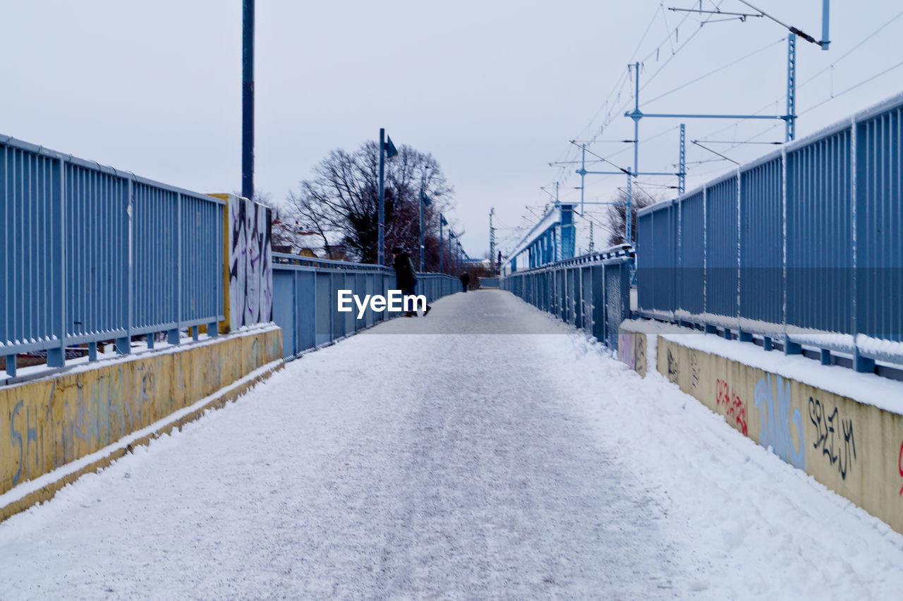 Snow covered walkway against sky during winter