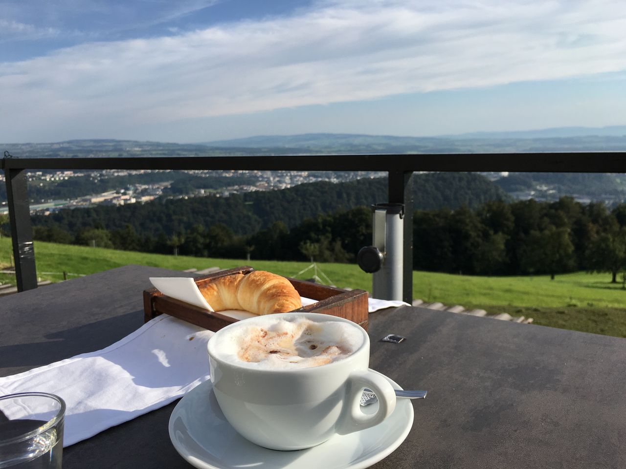 Croissant and coffee on table against mountain