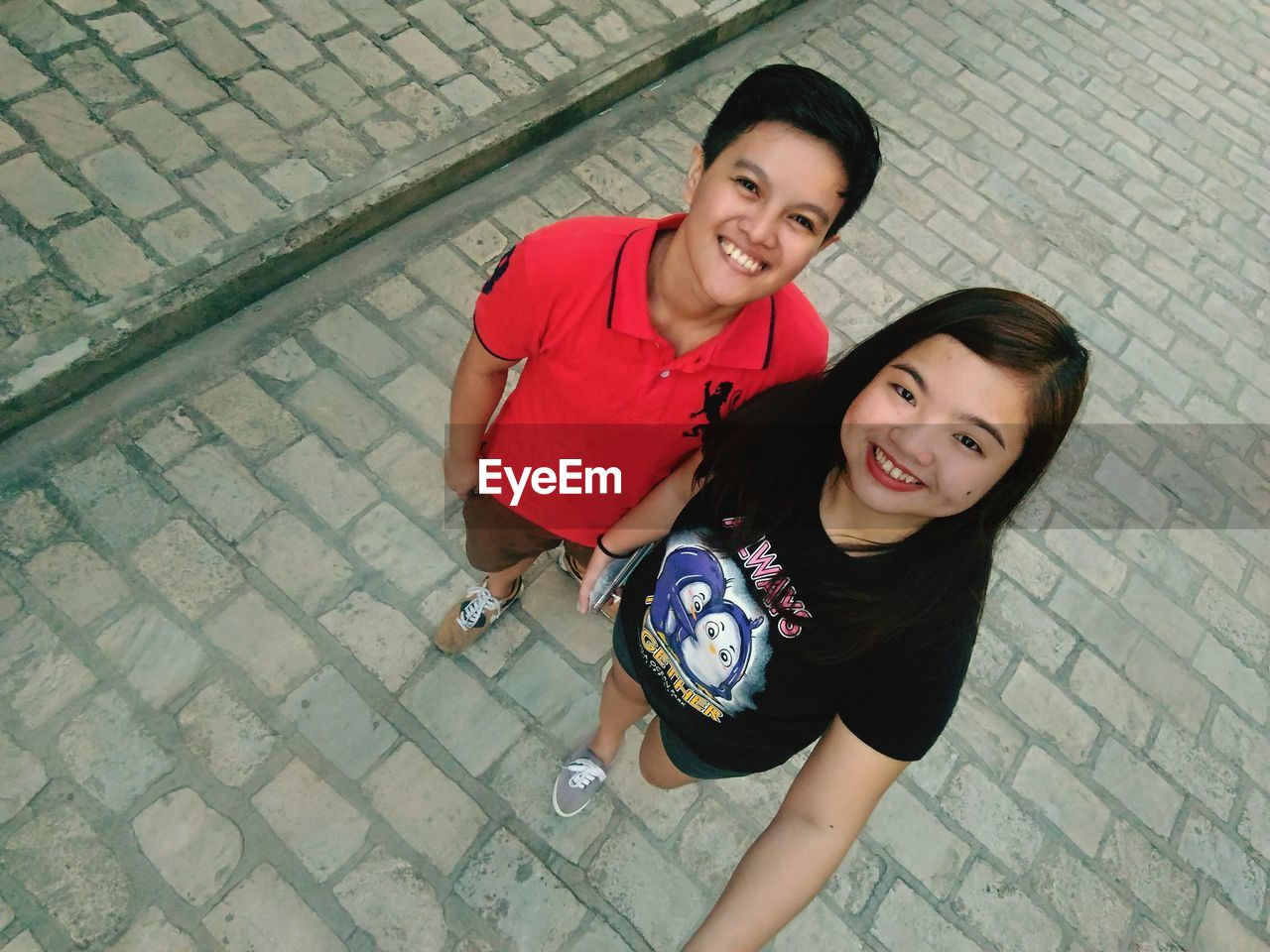 High angle portrait of friends smiling while standing on footpath