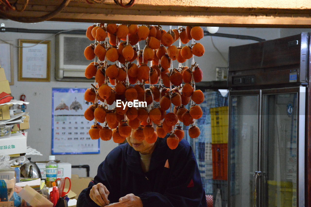 Woman by dried persimmons in store