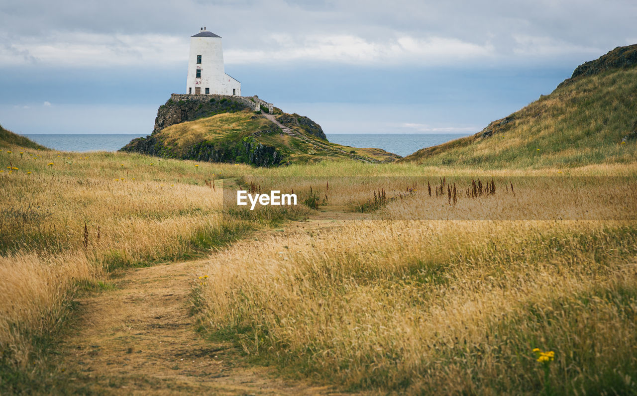 lighthouse on grassy field against sky