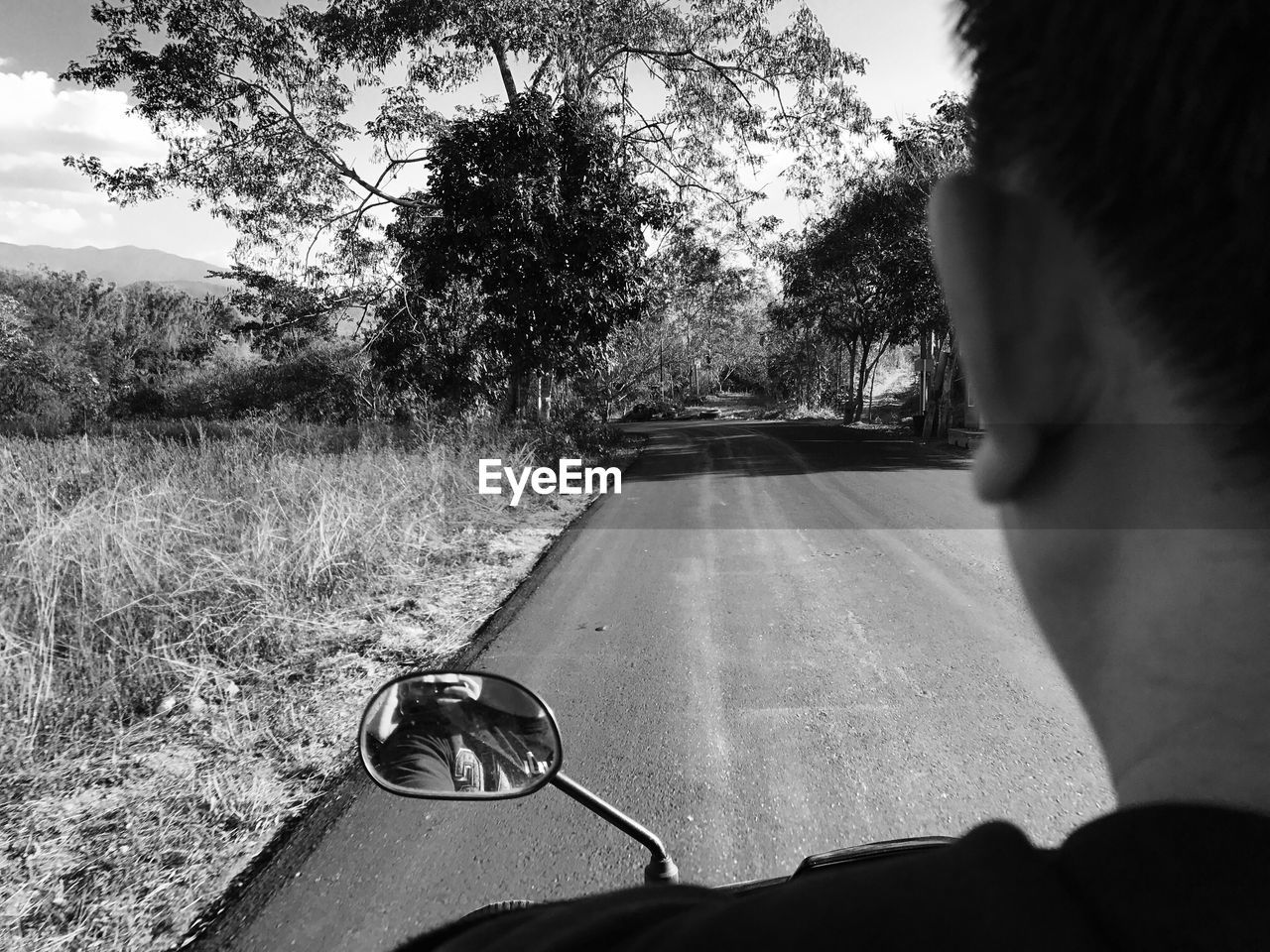 Close-up of man riding motor scooter on road