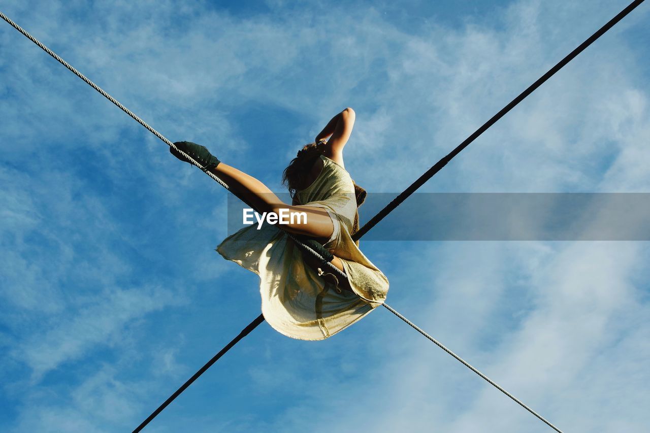 Low angle view of woman on rope against sky