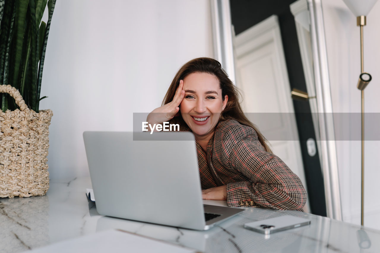 A business woman works online using a laptop phone and technology while sitting in the office