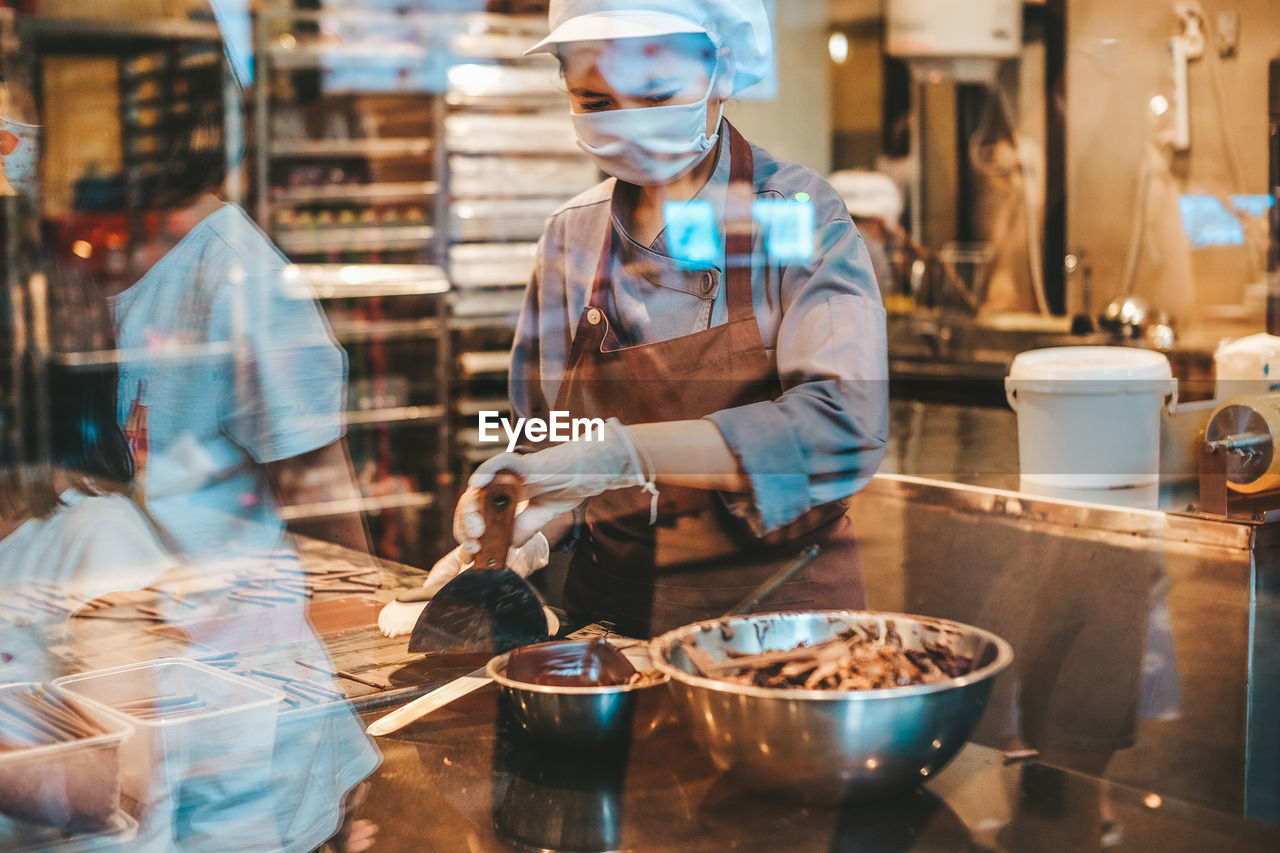 MIDSECTION OF WOMAN WORKING IN KITCHEN