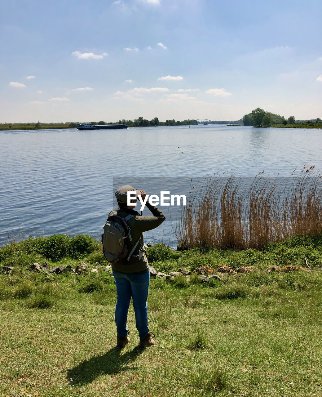 Rear view of woman watching over lake against sky