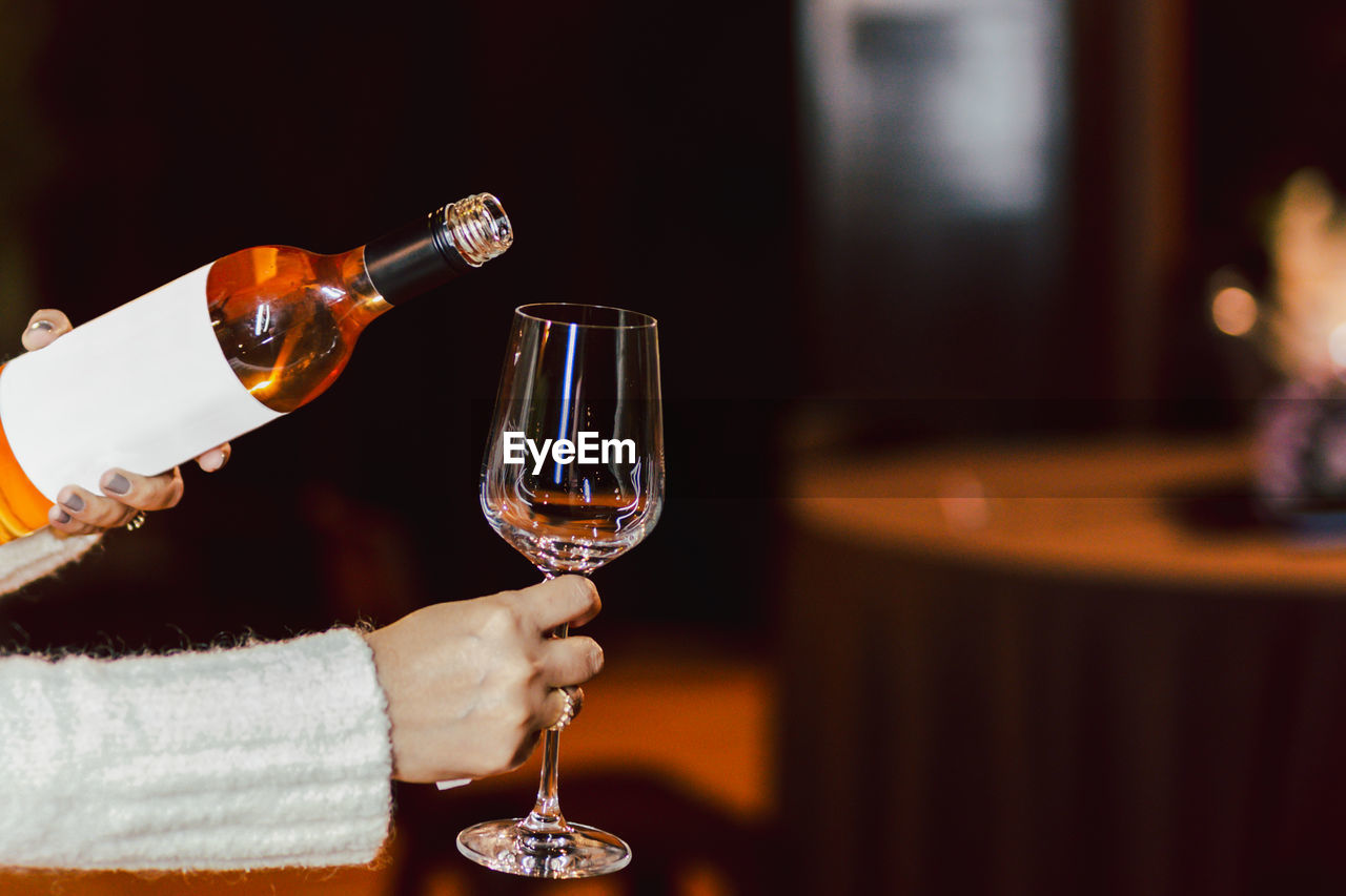 Woman hand holding bottle of rose wine and wine glass lifestyle concept.