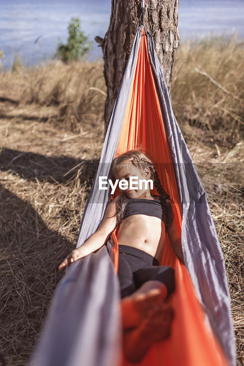 MIDSECTION OF WOMAN RELAXING ON FIELD
