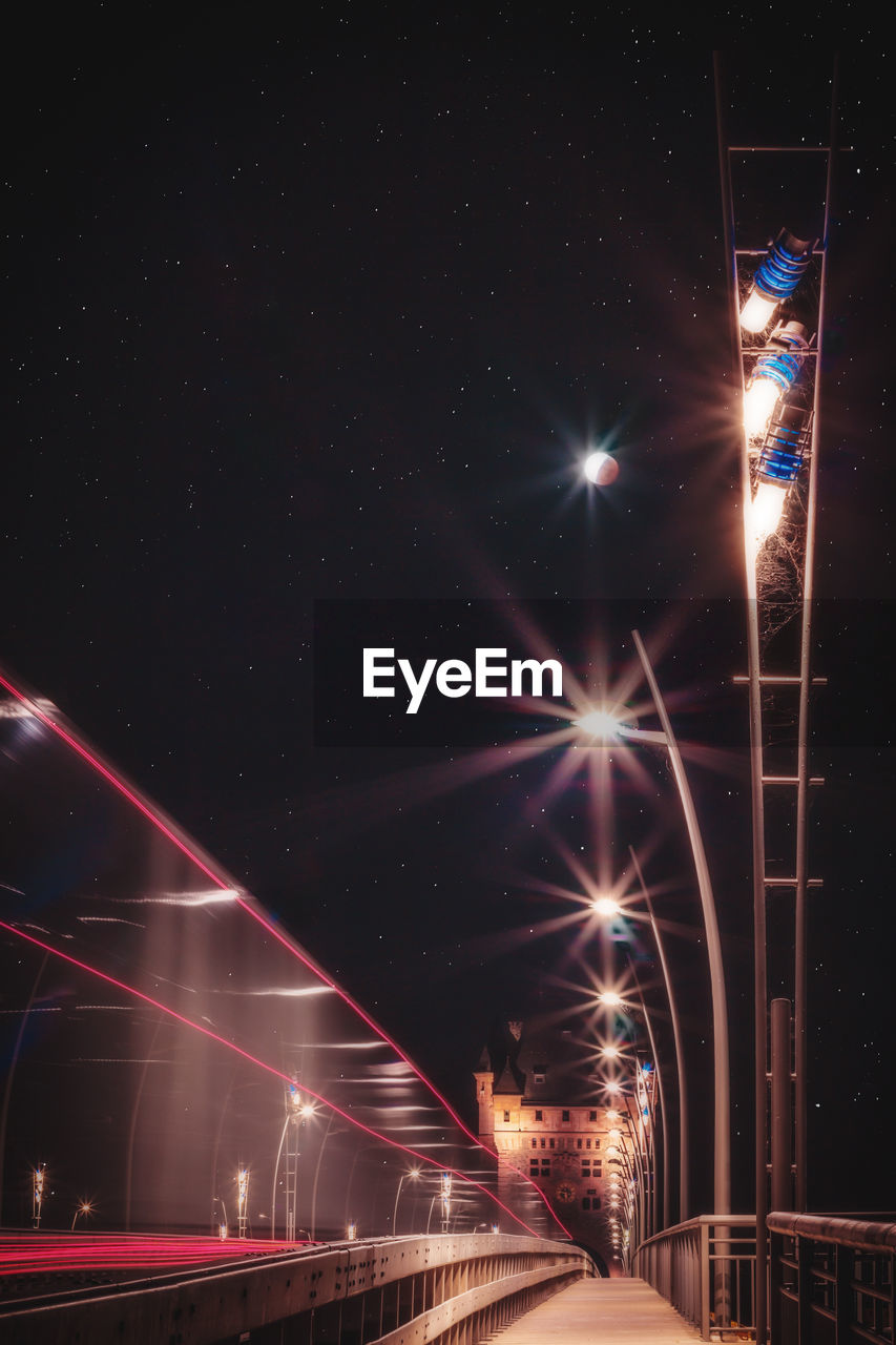 Low angle view of light trails in city against sky at night