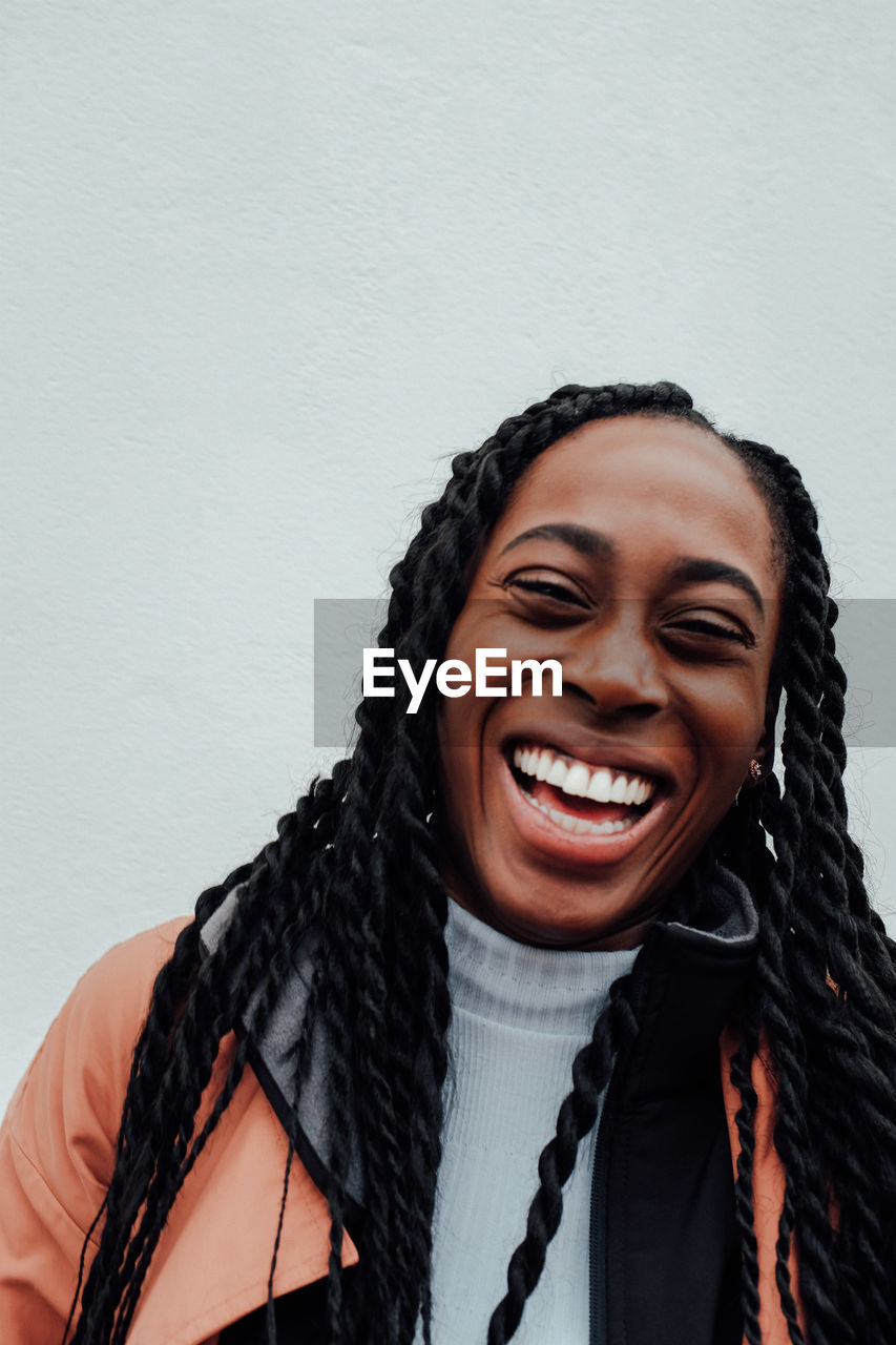 Portrait of cheerful young woman against wall