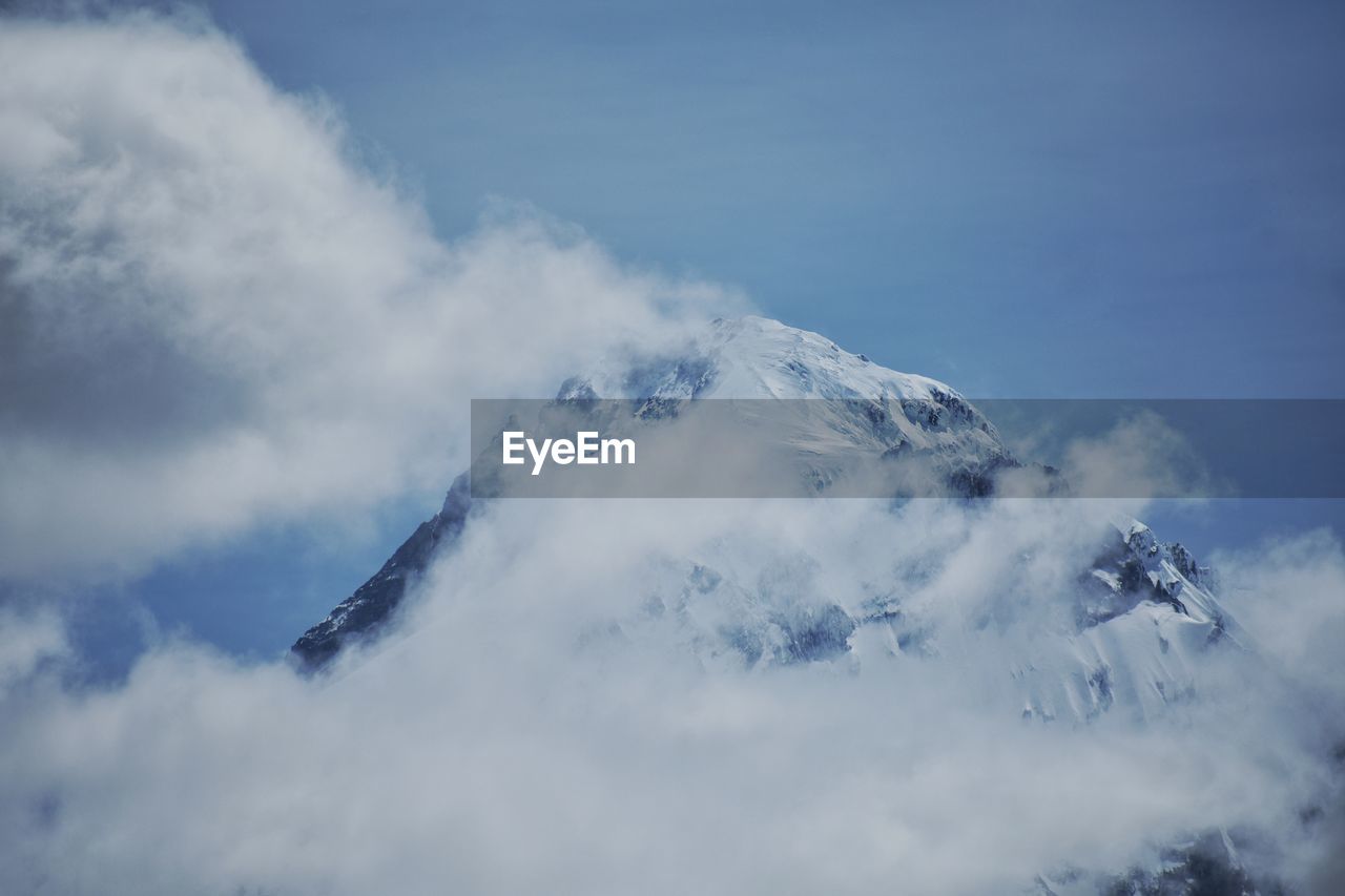 Snow capped mountain range surrounded by clouds