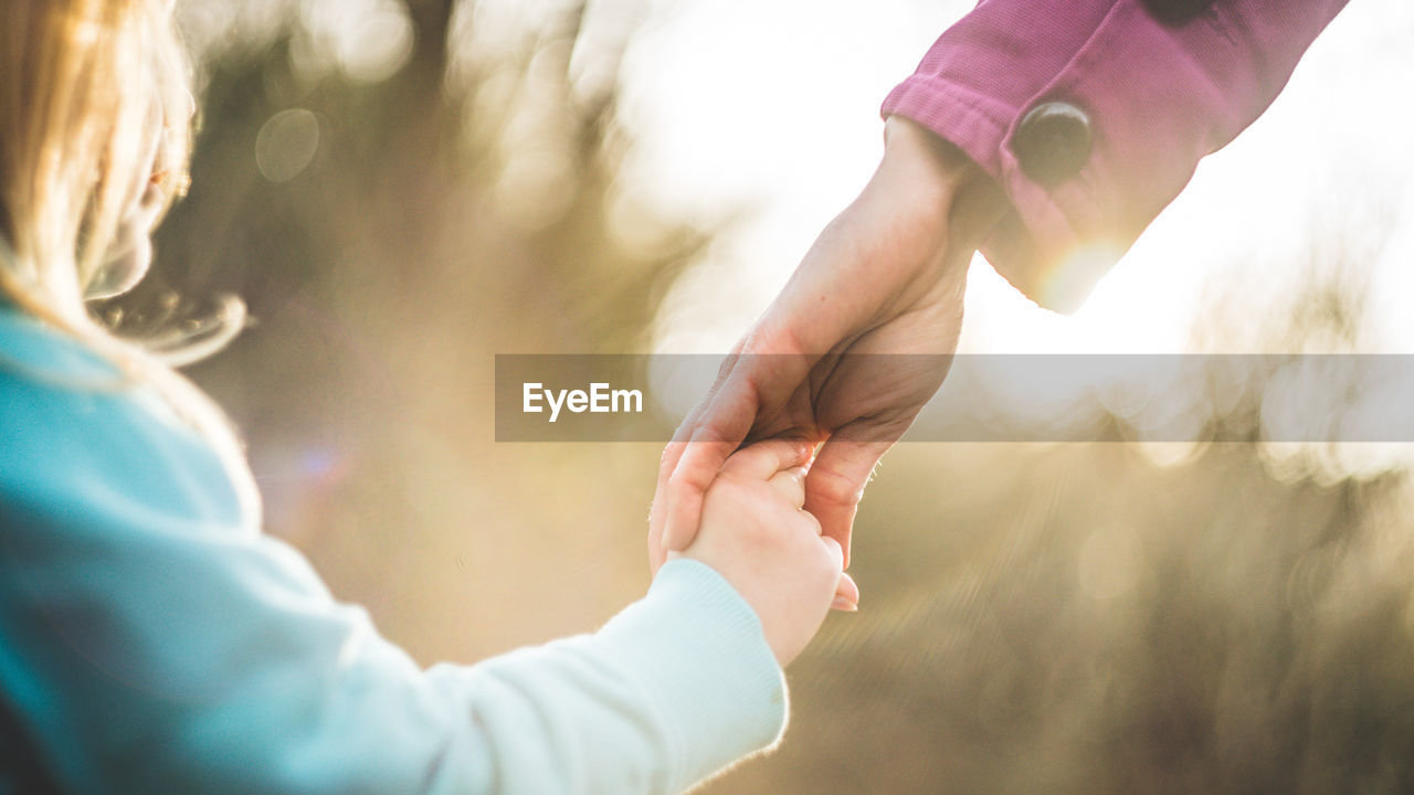 Close-up of girl holding mother hand