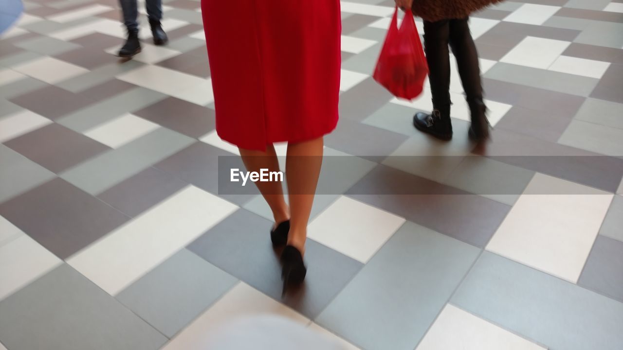 LOW SECTION OF WOMAN WALKING ON TILED FLOOR