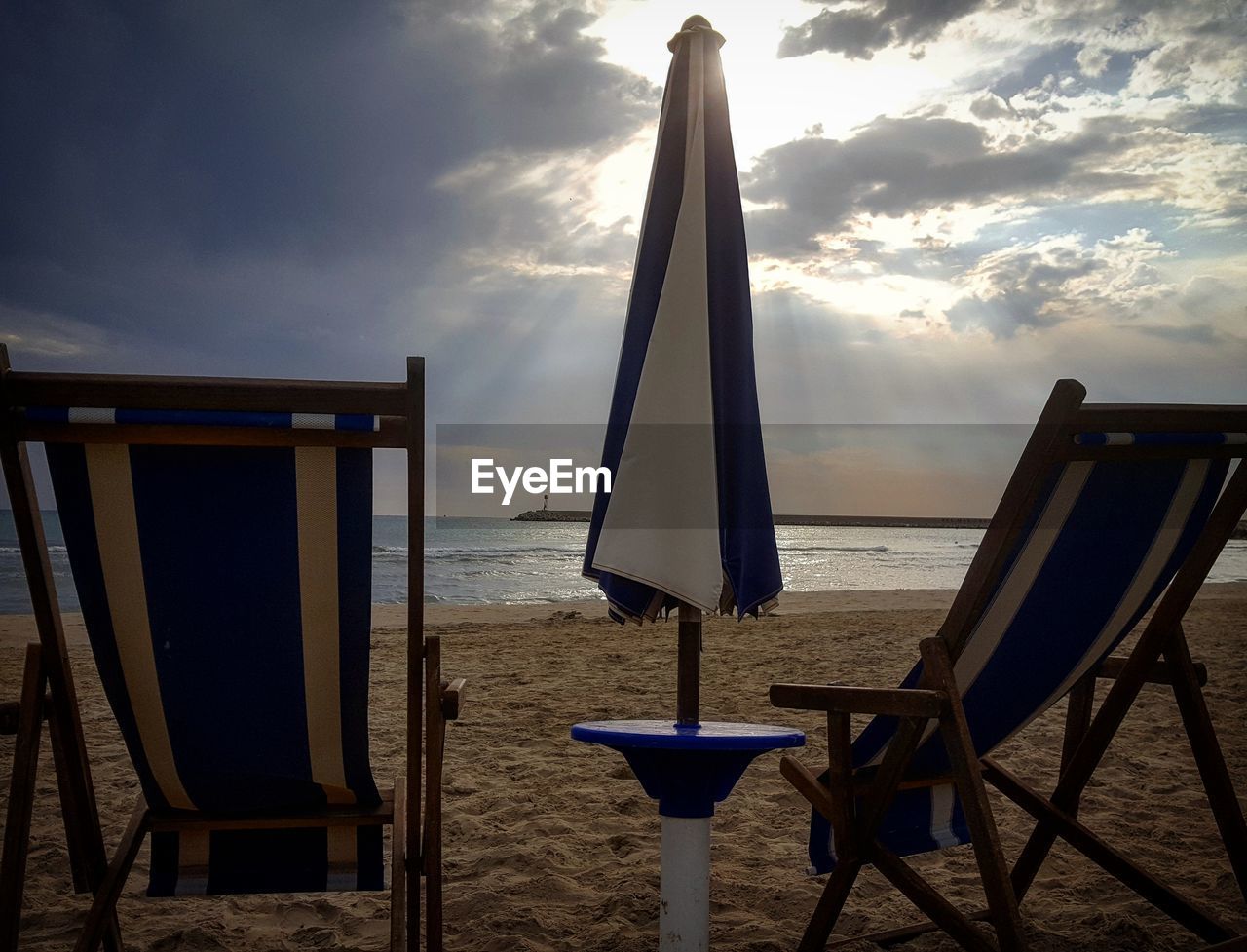 CHAIRS AND TABLES ON BEACH AGAINST SKY