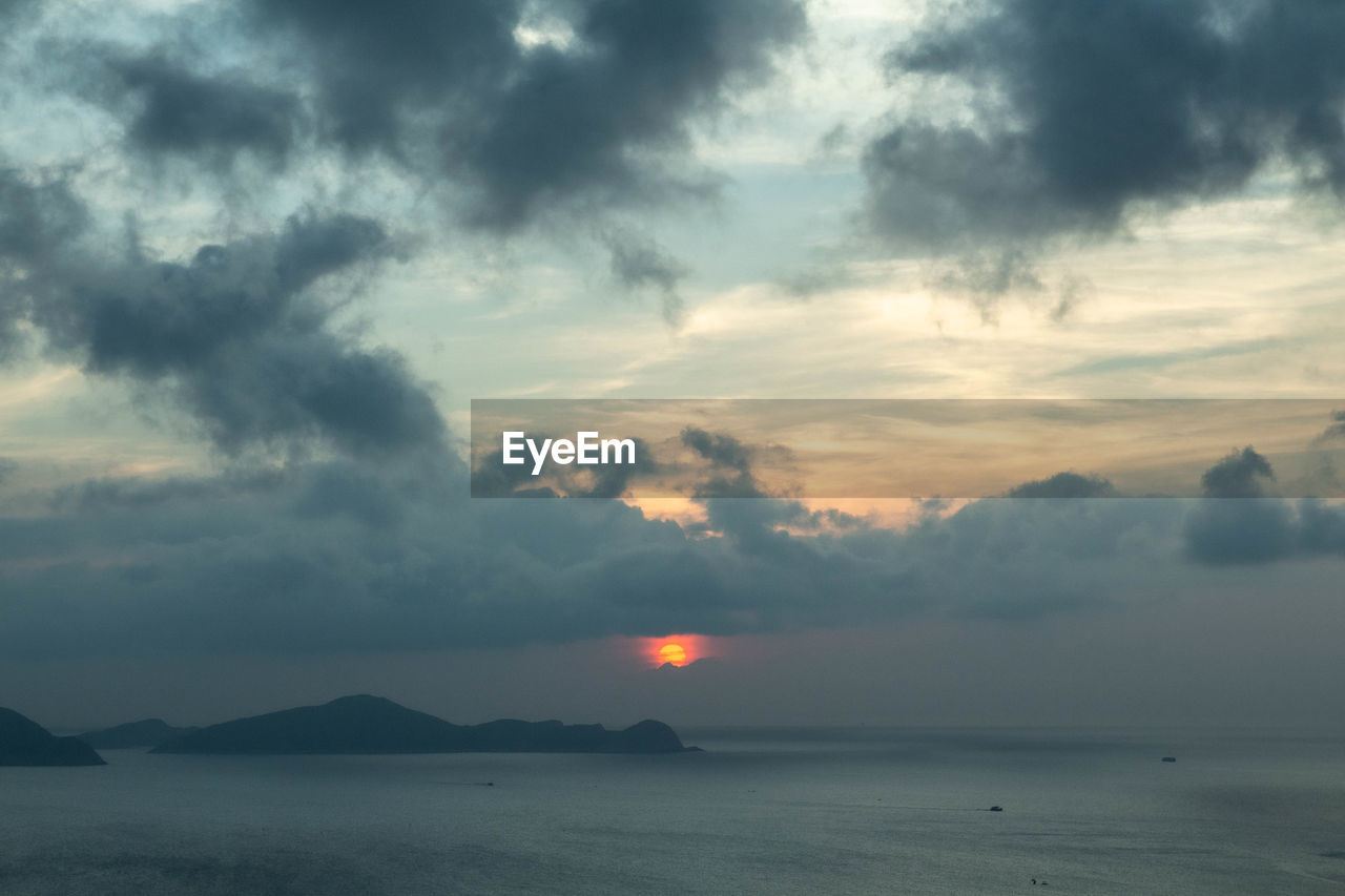 SCENIC VIEW OF SEA AGAINST CLOUDY SKY DURING SUNSET