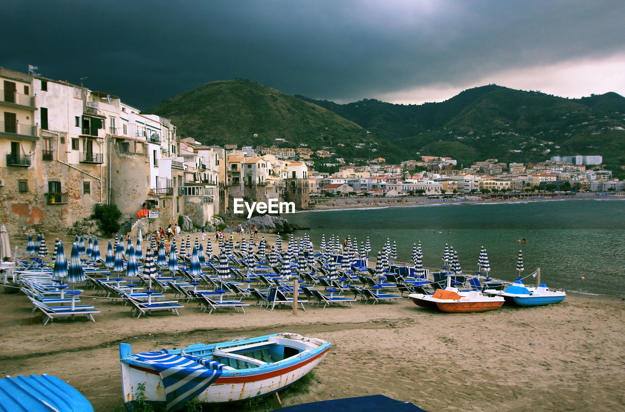 Boats moored on sea by buildings against sky