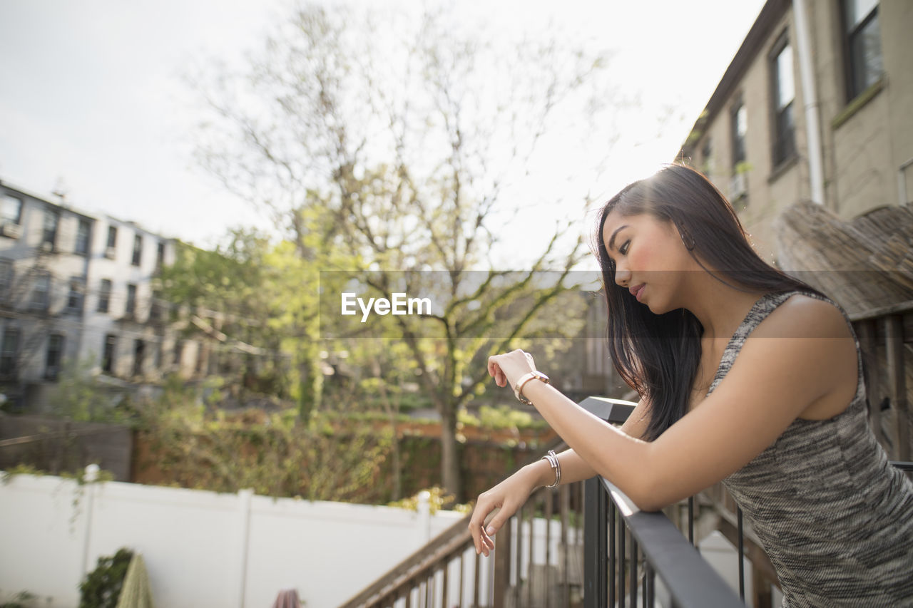 Young woman checking the time on her balcony