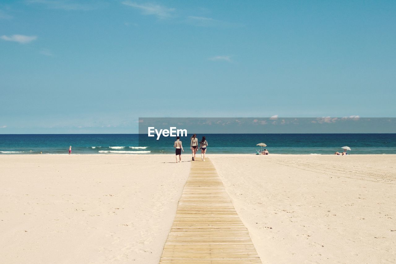 Man with women walking on boardwalk at beach