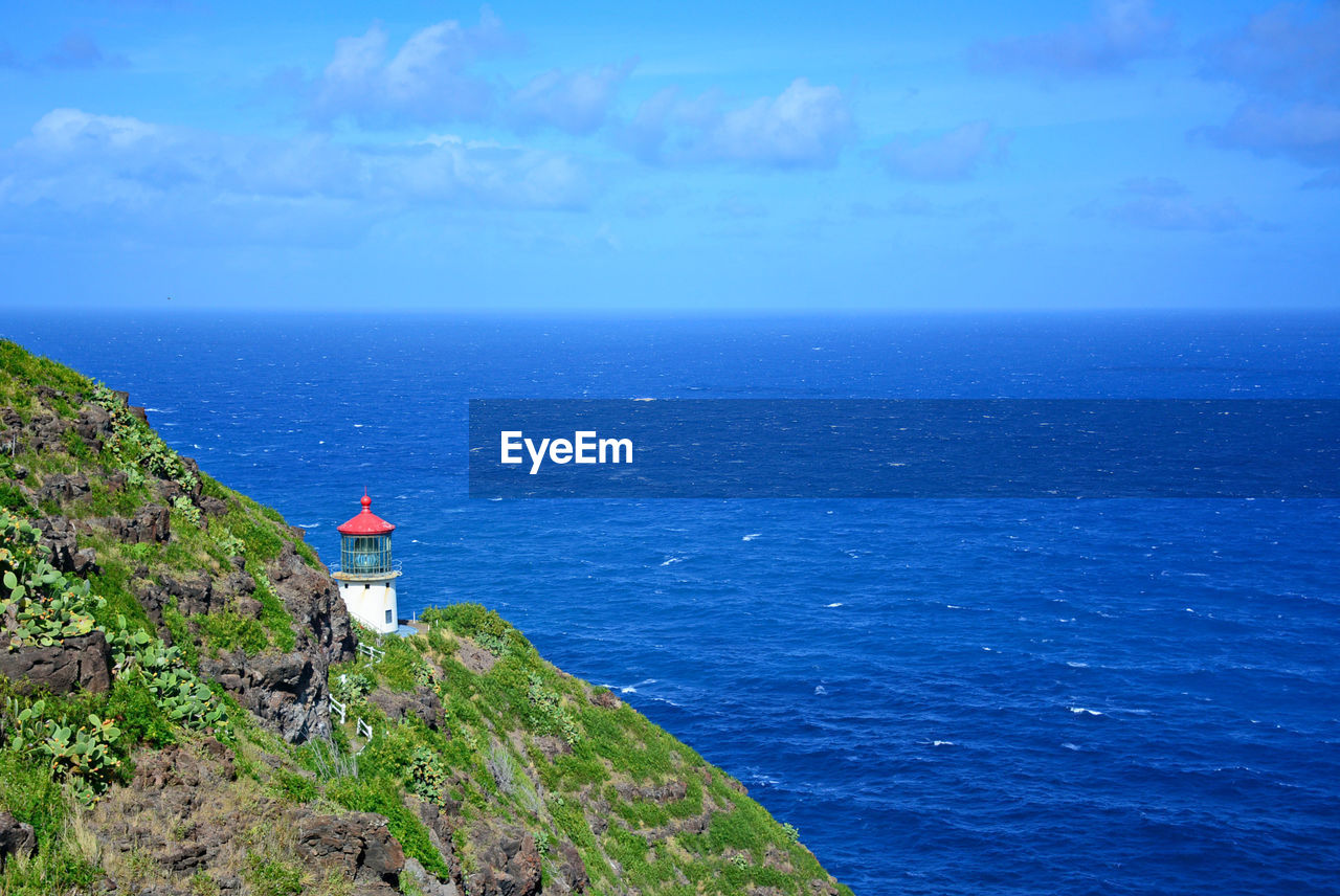 Scenic view of blue ocean with lighthouse against sky