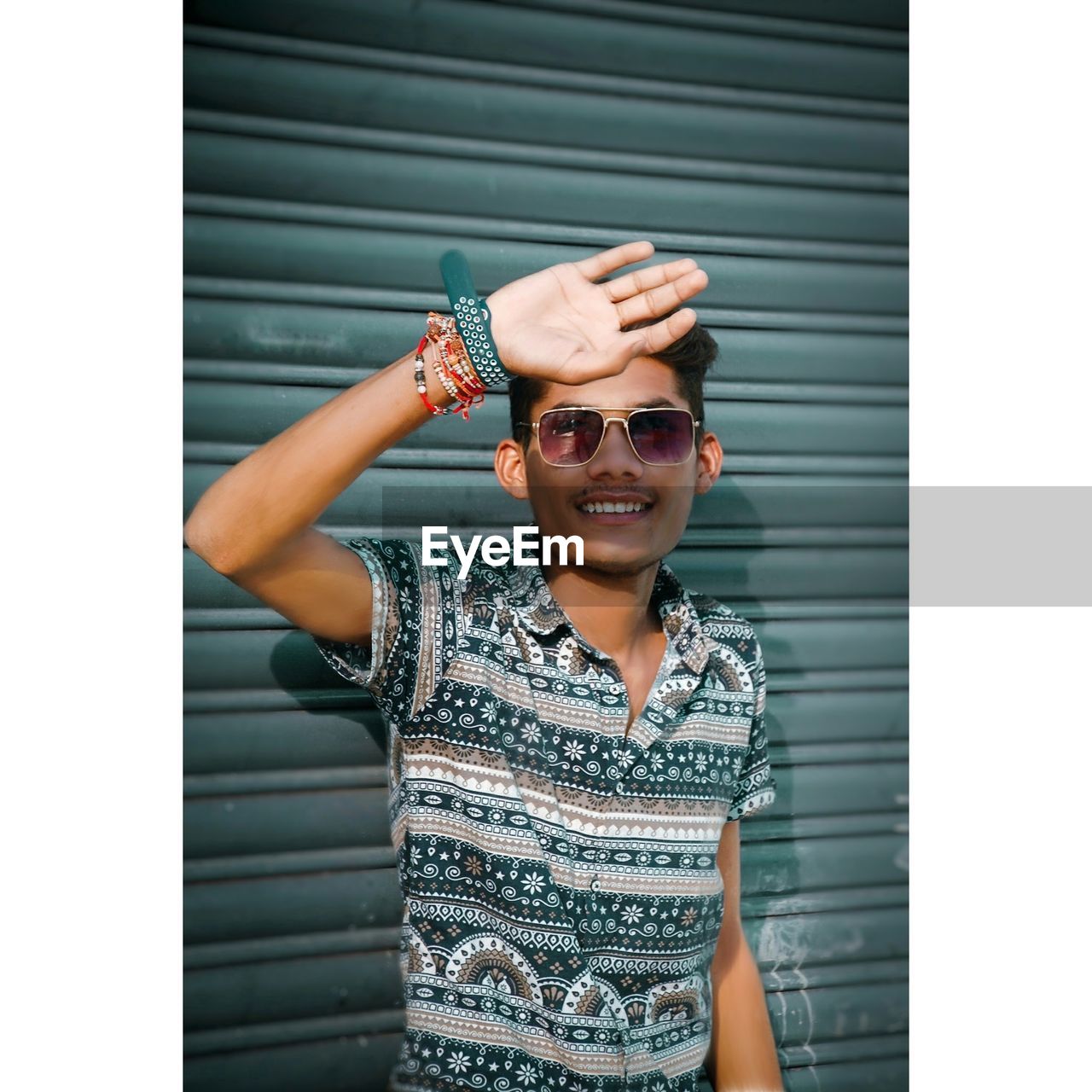 Portrait of young woman wearing sunglasses while standing against wall