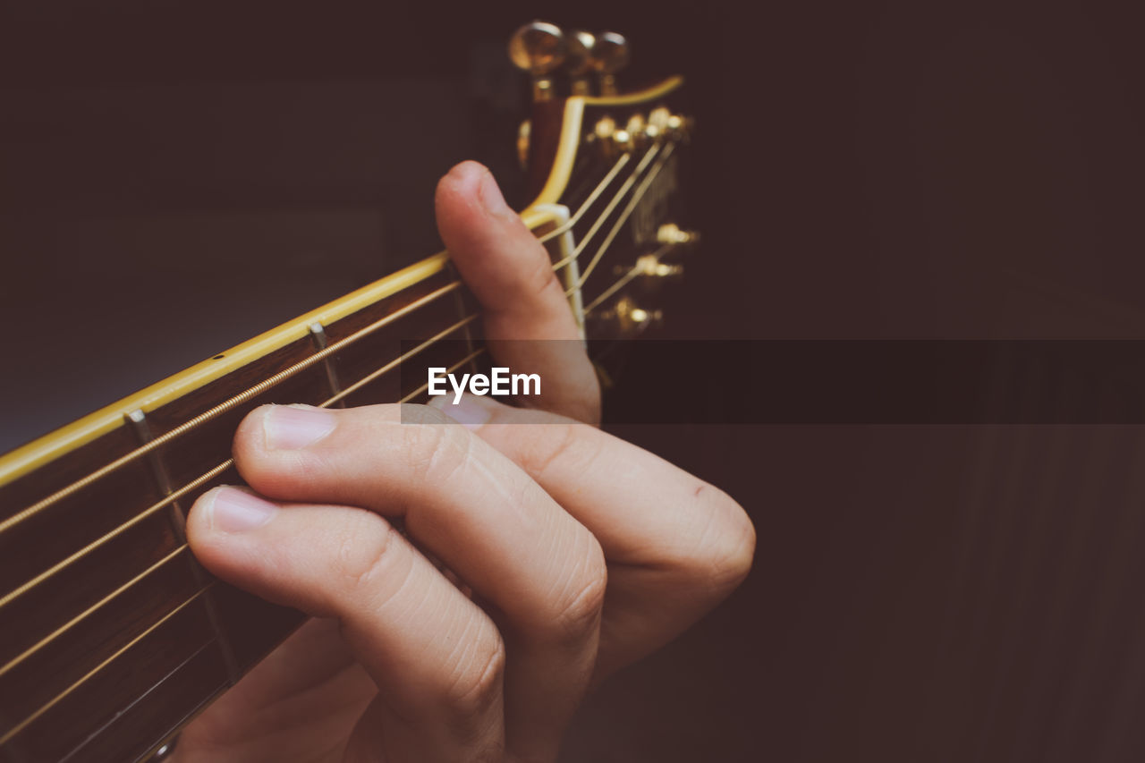 Close-up of person playing guitar against black background