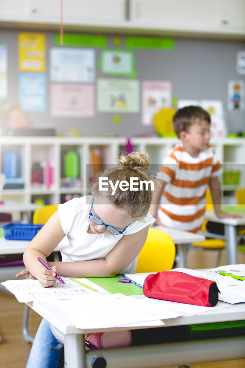 Girl writing in paper at kindergarten