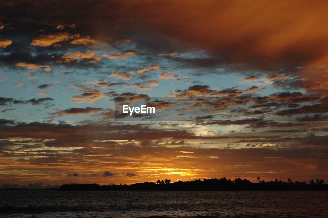 Scenic view of sea against dramatic sky during sunset