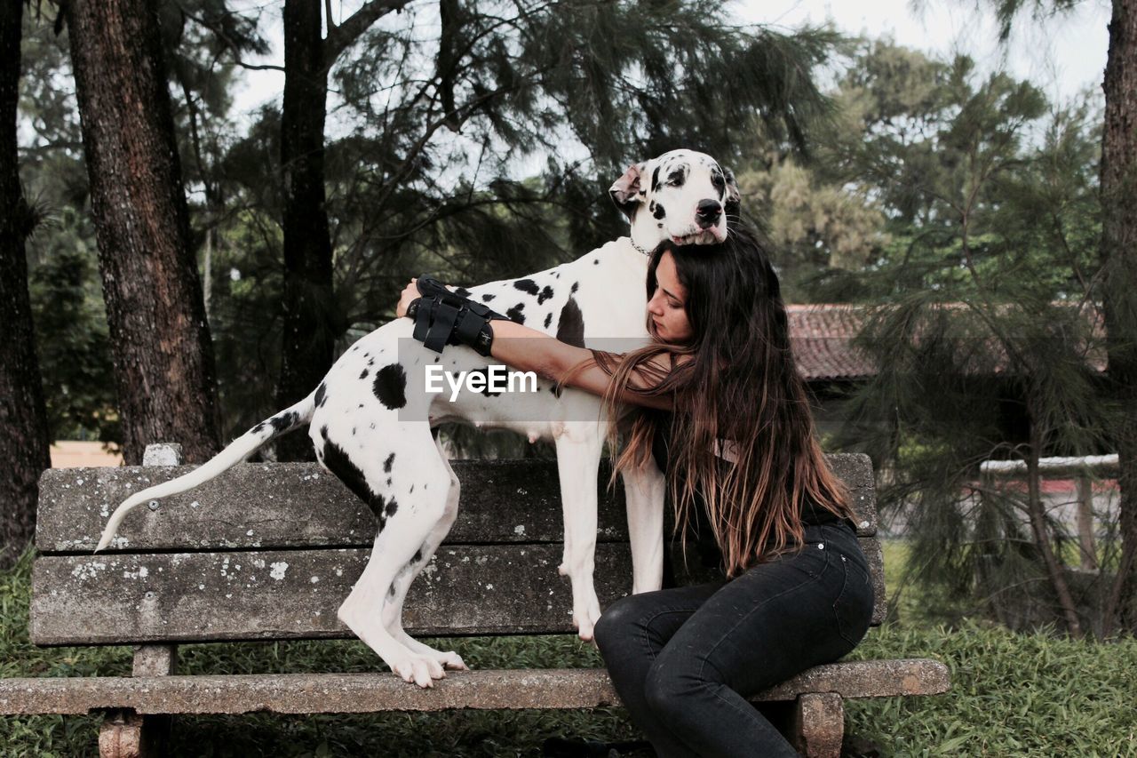 Woman hugging big dog on park bench