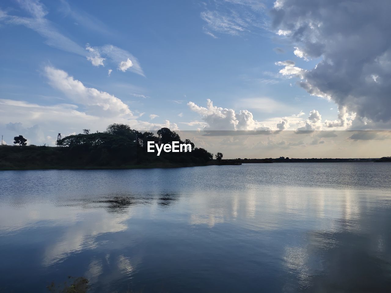 REFLECTION OF TREES IN LAKE AGAINST SKY