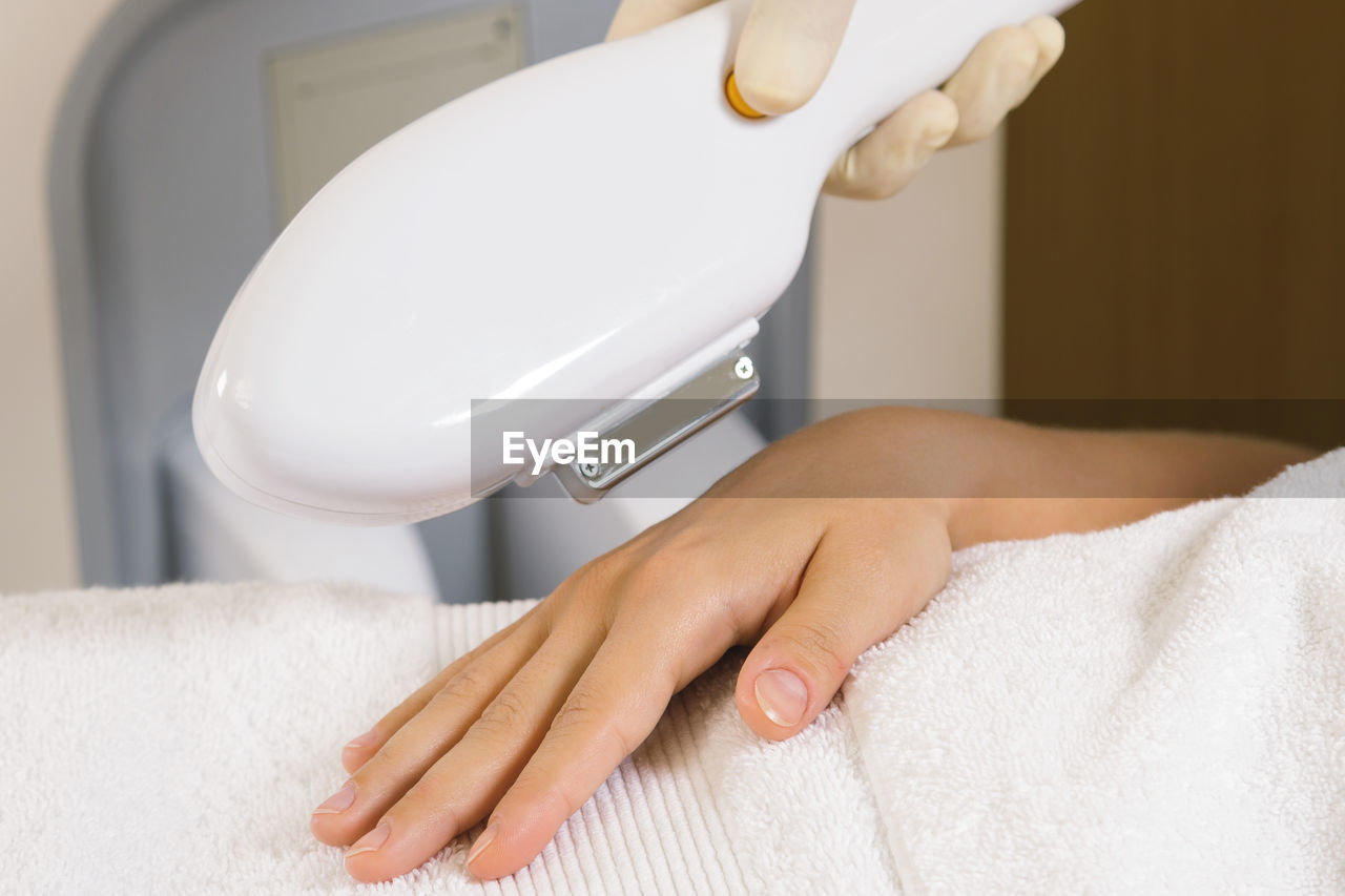 Cropped hands of woman doing laser treatment