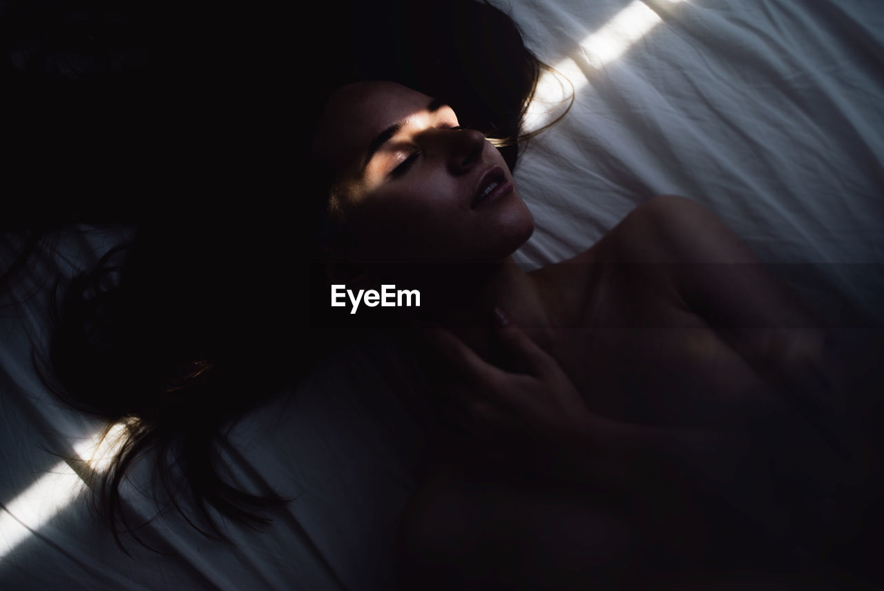 High angle view of topless sensuous woman sleeping on bed at home