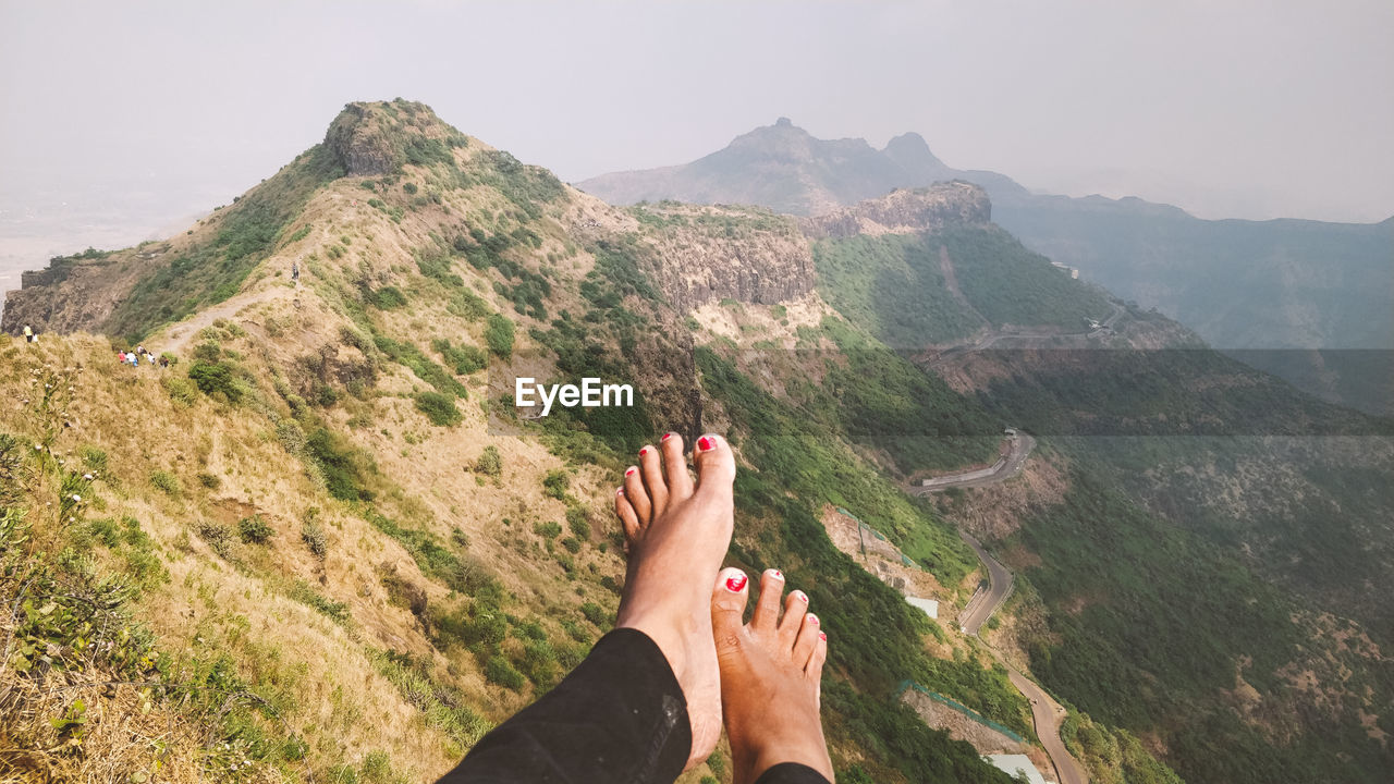 Low section of person on mountain against sky