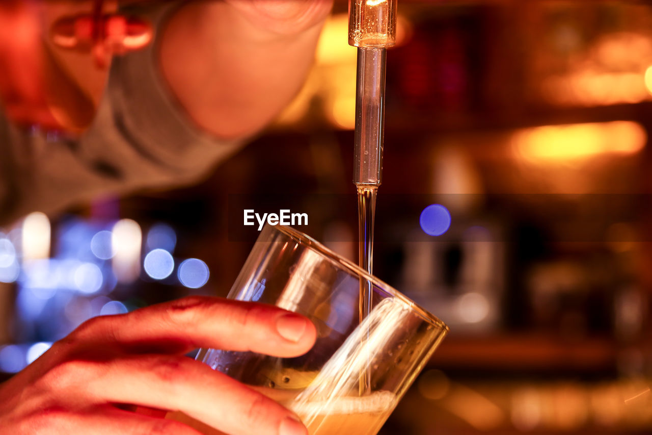 Close-up of man filling beer in glass from faucet at bar