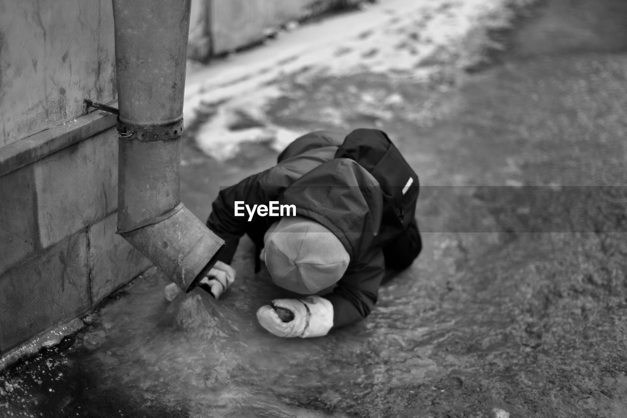 Boy looking at water flowing from pipe