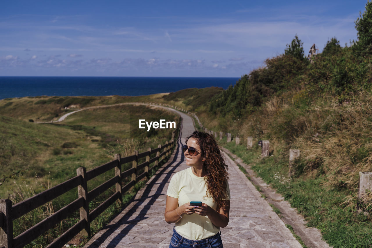 WOMAN STANDING BY RAILING AGAINST SKY