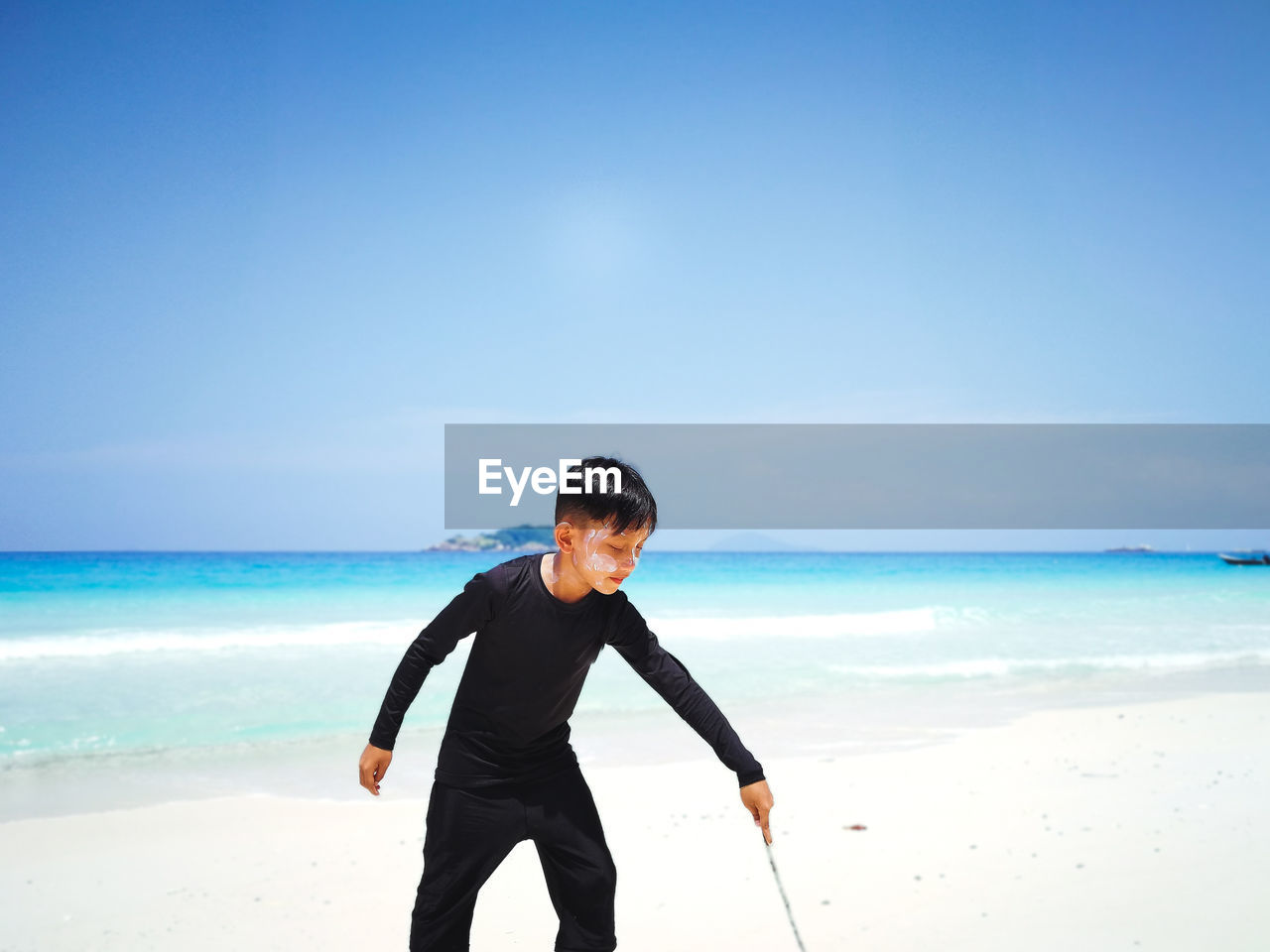 Boy standing on beach against sky