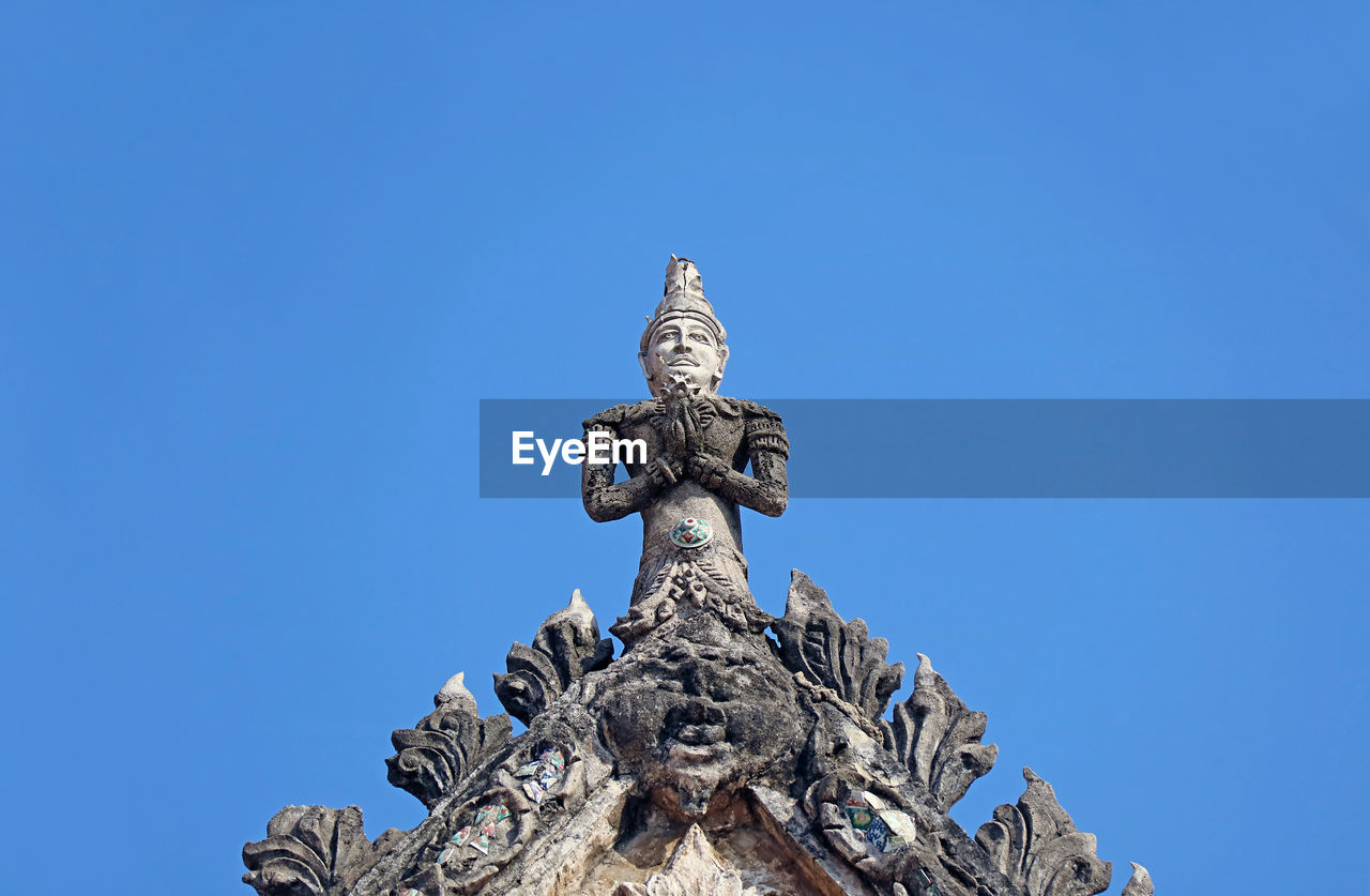 Deity sculpture on the pediment top of the old ordination hall of wat chomphuwek temple,  thailand