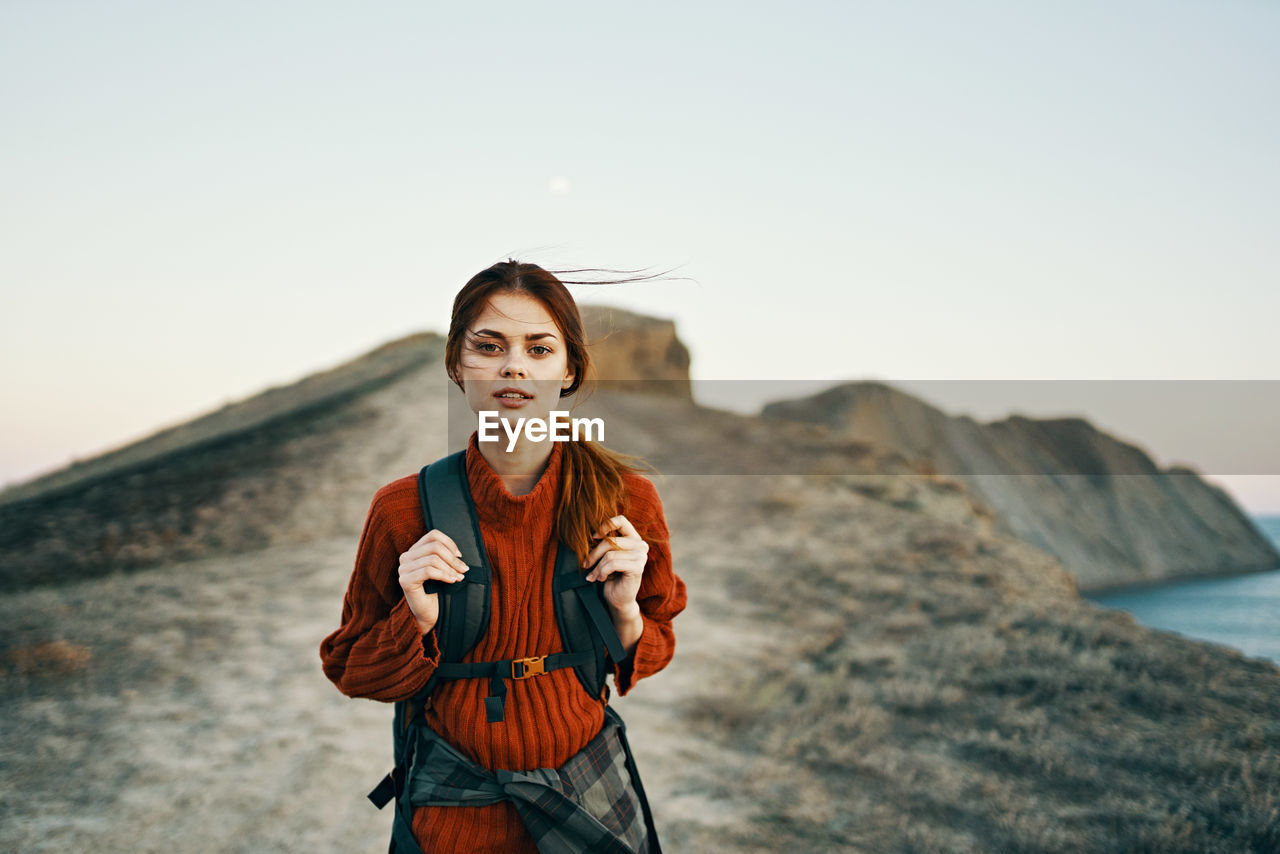 YOUNG WOMAN STANDING AGAINST SKY