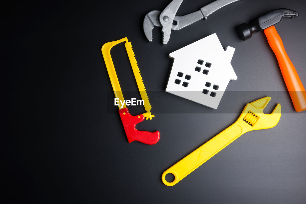 Directly above shot of plastic tools with model house on black background