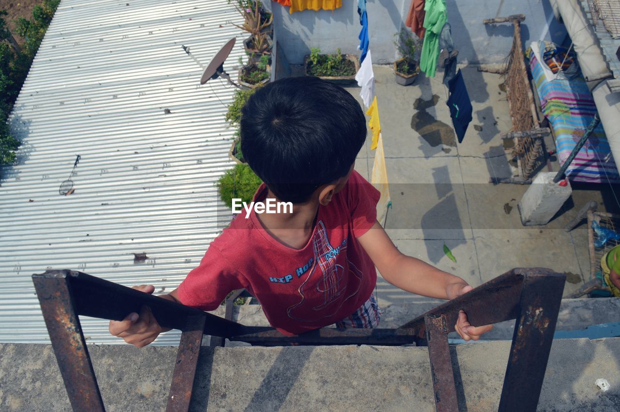 HIGH ANGLE VIEW OF SIBLINGS SITTING ON BENCH