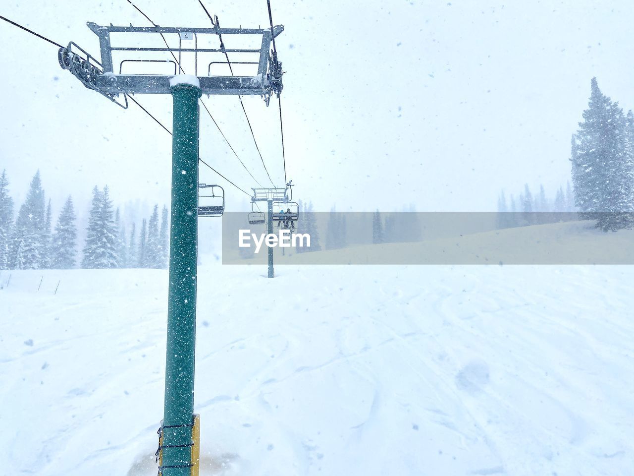 Ski lift on snow covered field against sky