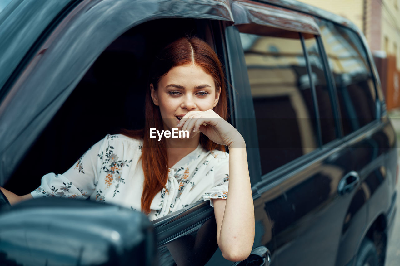 portrait of young woman using mobile phone while sitting in car