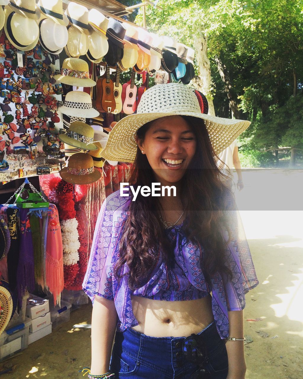 Cheerful beautiful woman standing against market stall