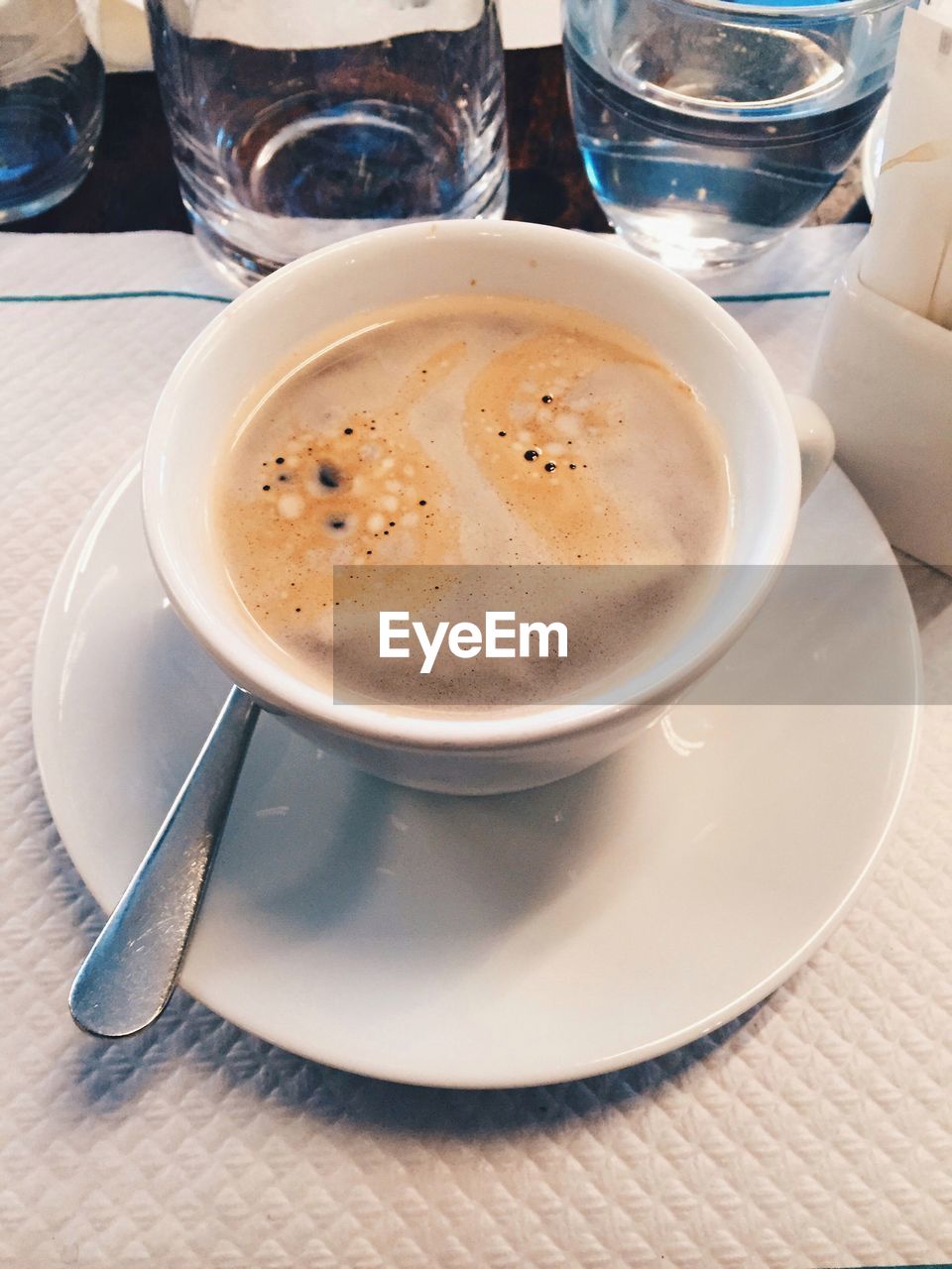 CLOSE-UP OF COFFEE CUP AND SPOON ON TABLE