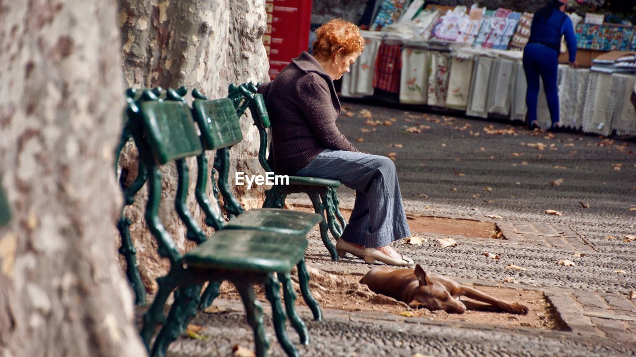 WOMAN SITTING ON BENCH IN PARK