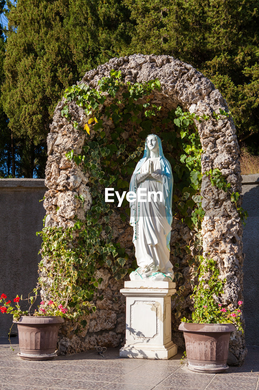 STATUE BY TREES AGAINST PLANTS