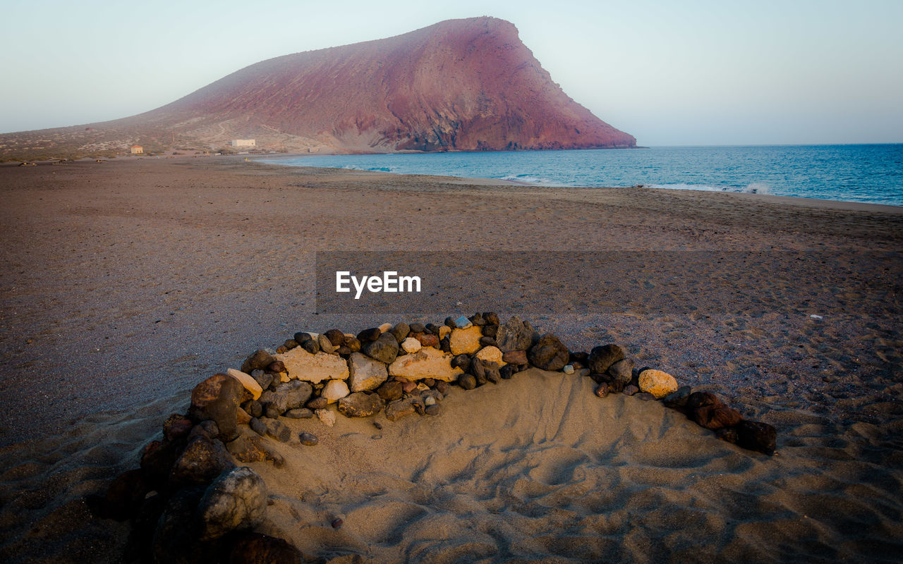 ROCKS ON BEACH AGAINST SKY DURING SUNSET